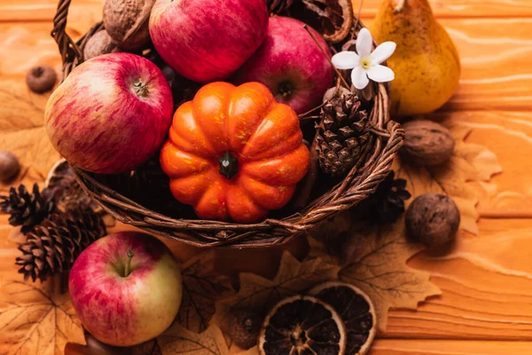 Wicker basket with autumnal harvest on wooden background — Stock Photo