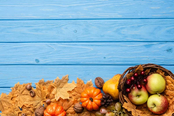 Ansicht der Herbsternte in Korb und Laub auf blauem Holzgrund — Stockfoto