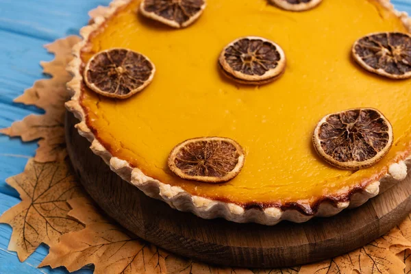 Vista da vicino di torta di zucca decorata con fogliame dorato su sfondo di legno blu — Foto stock