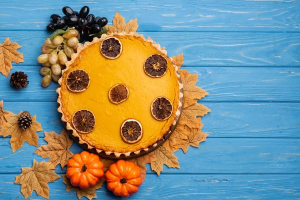 Top view of decorated pumpkin pie with golden foliage on blue wooden background — Stock Photo