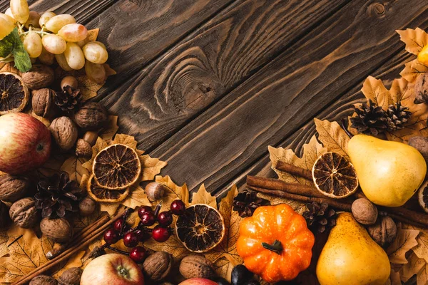 Top view of autumnal harvest and foliage on brown wooden background — Stock Photo