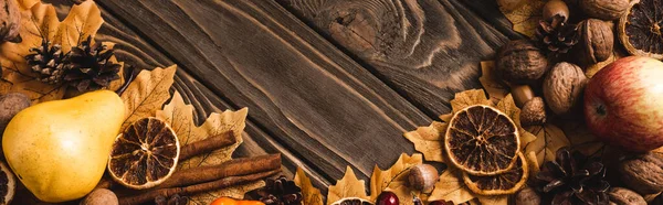 Top view of autumnal harvest and foliage on brown wooden background, panoramic shot — Stock Photo