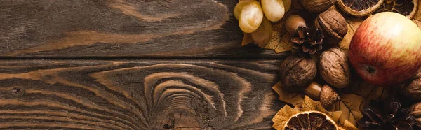 Top view of autumnal harvest and foliage on brown wooden background, panoramic shot — Stock Photo