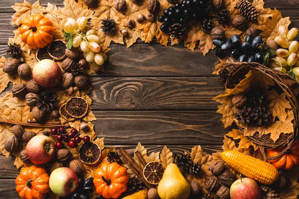 Vue de dessus du cadre rond fait de récolte automnale et de feuillage sur fond de bois brun — Stock Photo