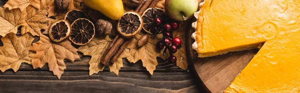 Top view of autumnal decoration and pumpkin pie on brown wooden background, panoramic shot — Stock Photo