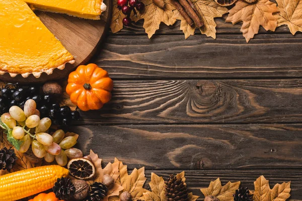 Top view of autumnal decoration and pumpkin pie on brown wooden background — Stock Photo