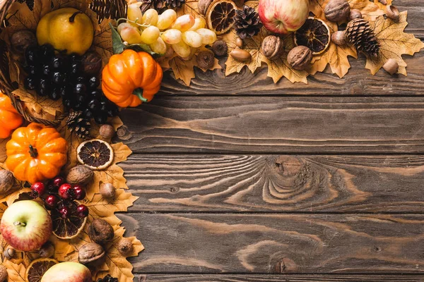 Vista dall'alto del raccolto autunnale sparso dal cesto su fogliame su fondo di legno marrone — Foto stock