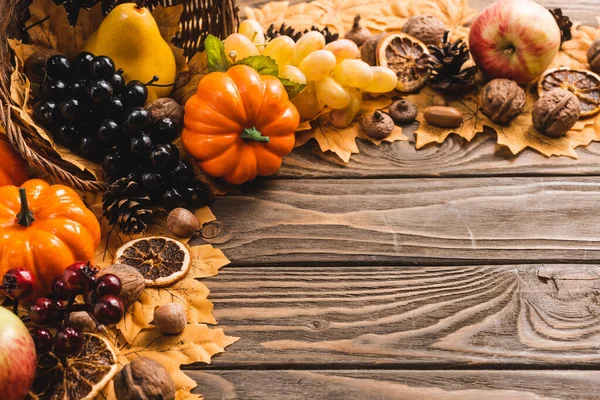 Autumnal harvest in basket on foliage on brown wooden background — Stock Photo