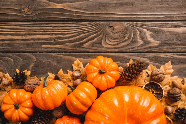 Top view of autumnal decoration and pumpkins on brown wooden background — Stock Photo