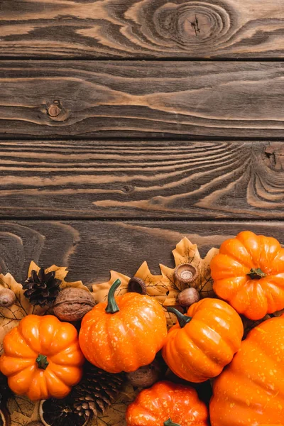 Top view of autumnal decoration and pumpkins on brown wooden background — Stock Photo