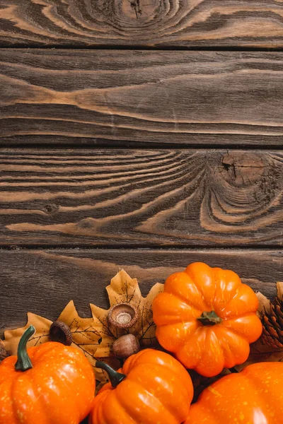 Top view of autumnal decoration and pumpkins on brown wooden background — Stock Photo