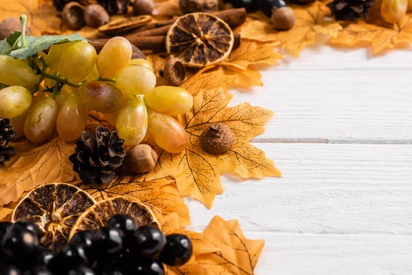 Selective focus of autumnal decoration and grapes on white wooden background — Stock Photo