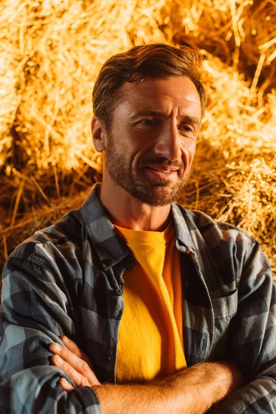 Rancher in plaid shirt near bale of hay looking away in sunshine — Stock Photo