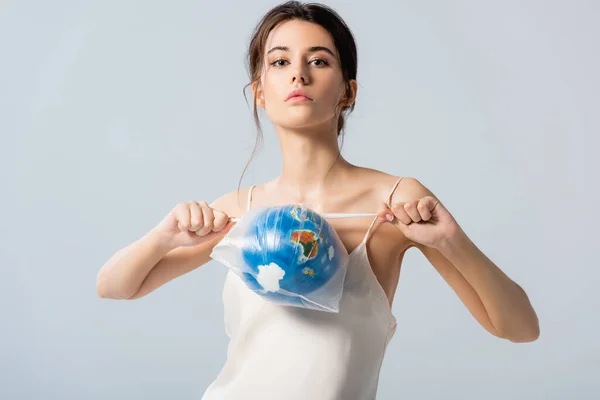 Молода жінка в шовковій сукні тримає поліетиленовий пакет з глобусом і дивиться на камеру ізольовано на білому, концепція екології — стокове фото