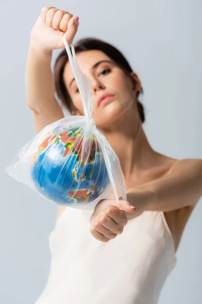 Foyer sélectif de la jeune femme tenant sac en plastique avec globe et regardant la caméra isolée sur blanc, concept d'écologie — Photo de stock