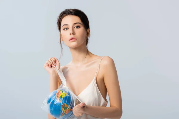 Brunette modèle tenant sac en plastique avec globe et regardant caméra isolée sur blanc, concept d'écologie — Photo de stock