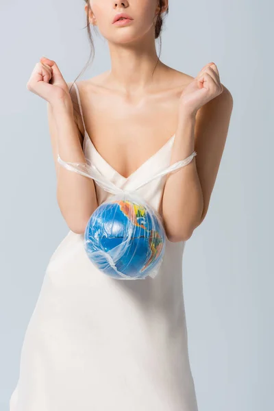 Vista parcial de mujer joven en vestido de seda sosteniendo bolsa de plástico con globo aislado en blanco, concepto de ecología - foto de stock