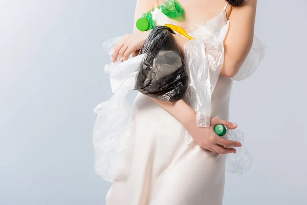 Vista parziale della donna che tiene bottiglie vuote e sacchetti di plastica su bianco, concetto di ecologia — Foto stock