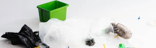Colpo panoramico di sacchetti di plastica e bottiglie vicino bidone della spazzatura su bianco, concetto di ecologia — Foto stock