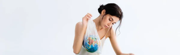 Image horizontale de la femme brune tenant un sac en plastique avec globe isolé sur blanc — Photo de stock