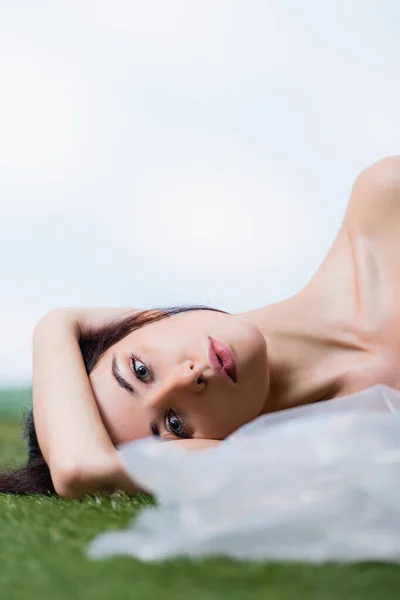 Selective focus of brunette woman lying near polyethylene on blue, ecology concept — Stock Photo