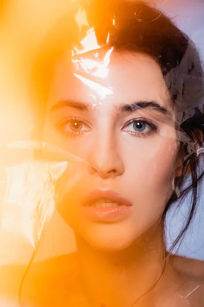 Nackte Frau blickt durch Polyethylen auf graues, ökologisches Konzept in die Kamera — Stockfoto