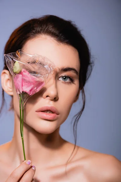 Nackte Frau, die Augen bedeckt, während sie Blumen in Polyethylen hält, isoliert auf grau, ökologisches Konzept — Stockfoto