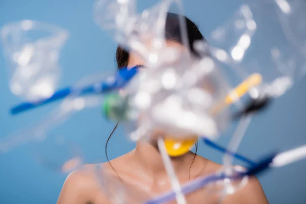 Foyer sélectif de la femme nue près de tomber tasses en plastique, cuillères et fourchettes sur le bleu, concept d'écologie — Photo de stock