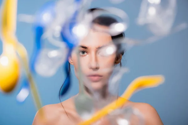 Foyer sélectif de la femme nue près de tomber tasses en plastique, cuillères et fourchettes sur le bleu, concept d'écologie — Photo de stock