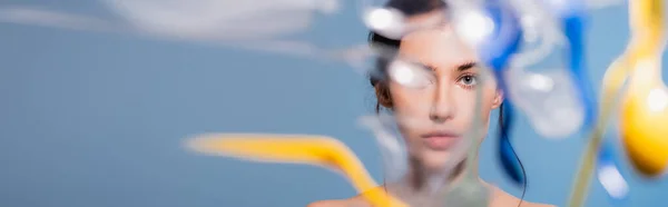 Colpo panoramico di donna nuda vicino cadere bicchieri di plastica, cucchiai e forchette su blu, concetto di ecologia — Foto stock
