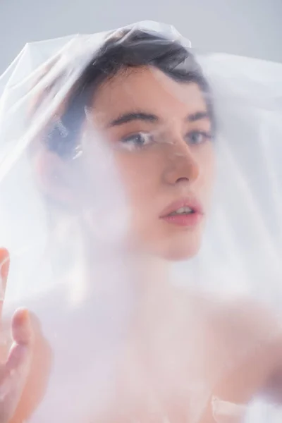 Jeune femme brune recouverte de polyéthylène isolé sur gris, concept écologie — Photo de stock