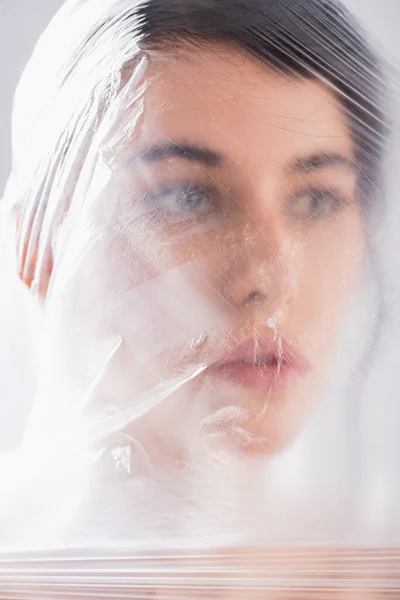 Young brunette model covered with polyethylene looking away, ecology concept — Stock Photo