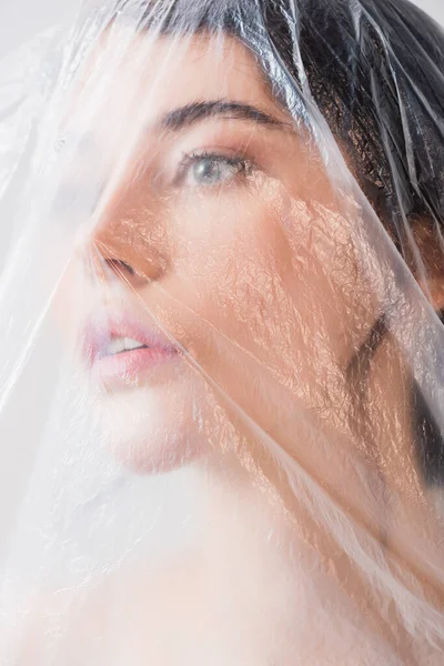 Jeune femme brune regardant à travers le polyéthylène, concept d'écologie — Photo de stock