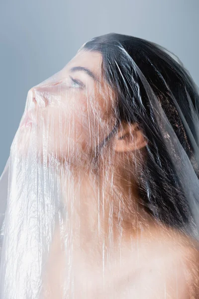 Young model looking through polyethylene isolated on grey, ecology concept — Stock Photo