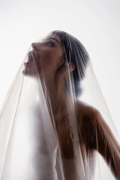 Mulher morena gritando através de polietileno isolado em branco, conceito de ecologia — Fotografia de Stock