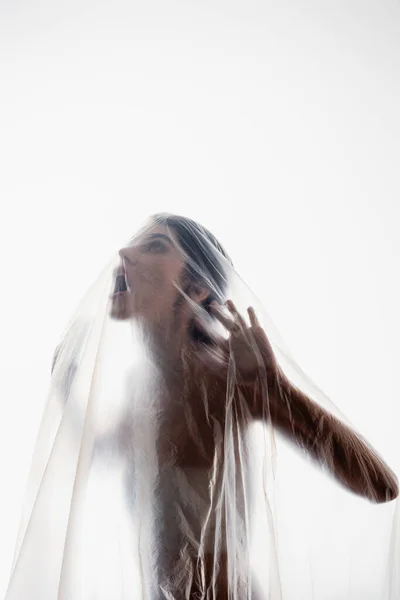 Verängstigte brünette Frau schreit durch Polyethylen isoliert auf weißem, ökologischem Konzept — Stockfoto