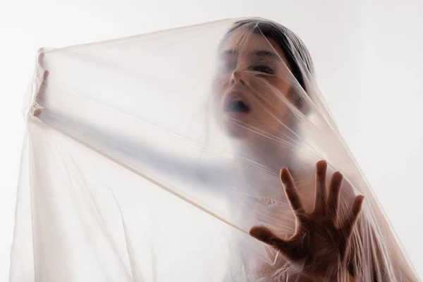 Mulher gritando através de polietileno isolado em branco, conceito de ecologia — Fotografia de Stock