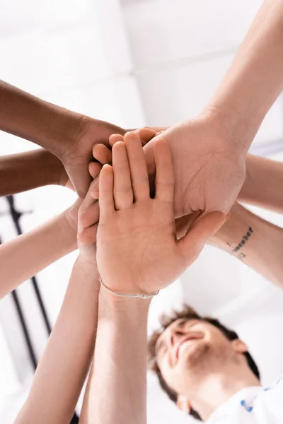 Вид знизу на багатоетнічних добровольців, які тримають руки в благодійному центрі — стокове фото