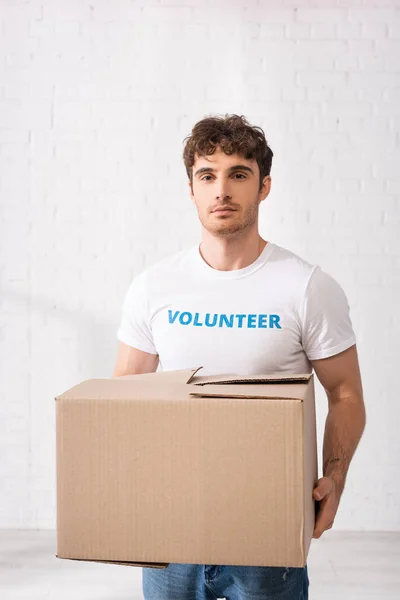 Young volunteer with carton box in charity center — Stock Photo