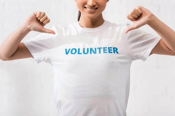 Vista recortada del voluntario apuntando a la camiseta con letras — Stock Photo