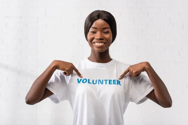 Afrikanischer Freiwilliger zeigt mit Fingern auf T-Shirt mit Schriftzug in Charity-Zentrum — Stockfoto