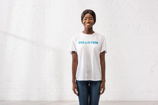 Voluntário afro-americano em camiseta branca com letras olhando para a câmera — Fotografia de Stock