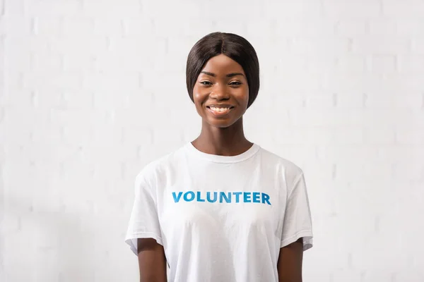 African american volunteer in white t-shirt looking at camera in charity center — Stock Photo