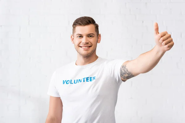 Volunteer in t-shirt with lettering showing thumb up — Stock Photo