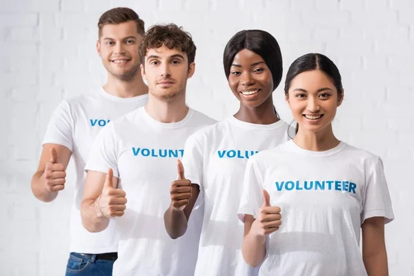 Selective focus of multiethnic volunteers showing like gesture at camera — Stock Photo