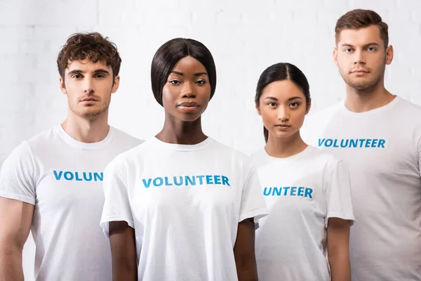 Enfoque selectivo de la mujer afroamericana mirando a la cámara cerca de voluntarios multiétnicos - foto de stock