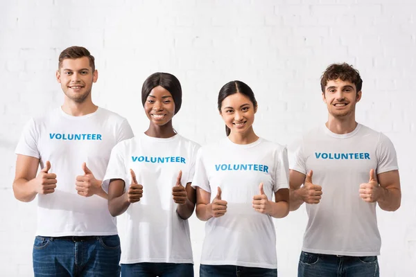 Young multiethnic volunteers showing approval gesture at camera — Stock Photo