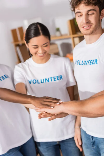 Enfoque selectivo de voluntarios multiétnicos tomados de la mano en el centro de caridad - foto de stock