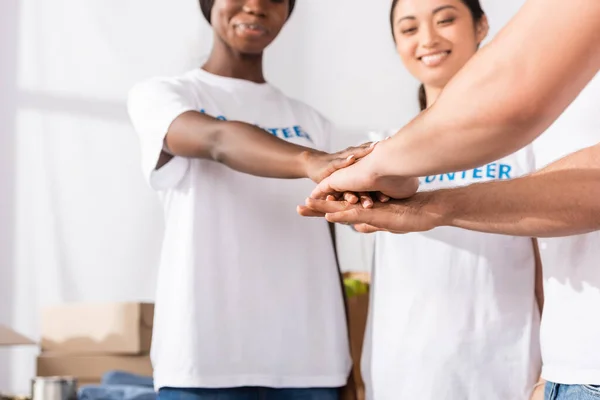 Селективный фокус мультикультурных волонтеров, держащихся за руки в благотворительном центре — стоковое фото