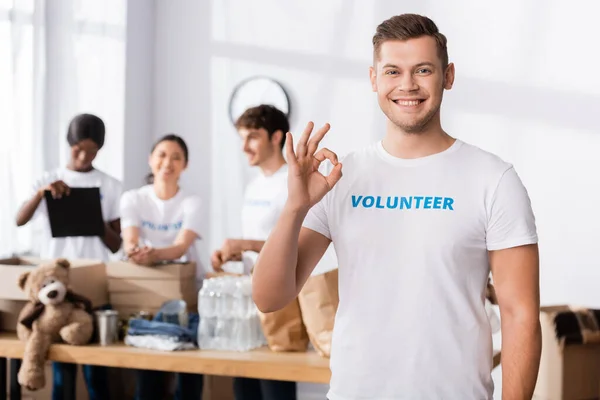 Focus selettivo del volontario che mostra un gesto positivo alla telecamera nel centro di beneficenza — Foto stock